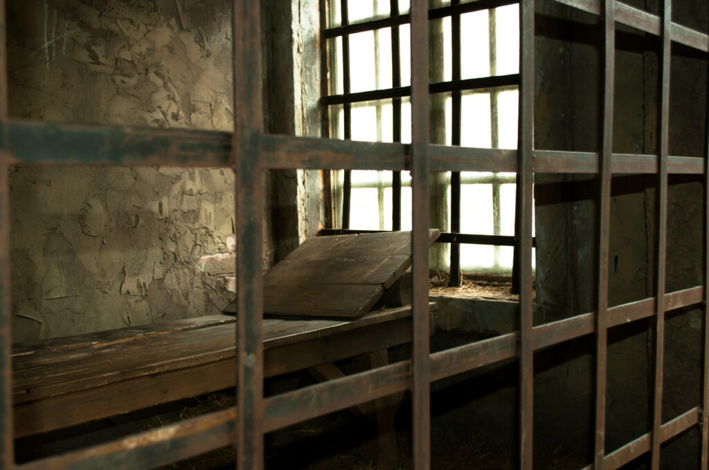 Wooden bed in a medieval prison cell near the window